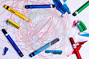 A Child`s Crayon Drawing/scribbles with Generic Crayons and torn label pieces from stripping the label.  The center of the image photo