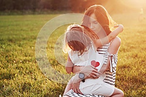 The child`s daughter congratulates her mother and gives her a postcard. Mother and girl smile and hug.