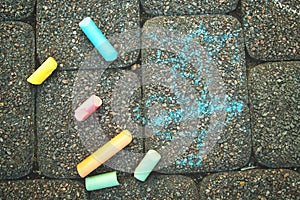 A child`s drawing and colorful chalks on a street, a sidewalk or a pavement. Children`s drawing with chalk on the