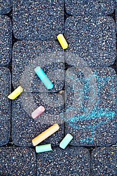 A child`s drawing and colorful chalks on a street, a sidewalk or a pavement. Children`s drawing with chalk on the