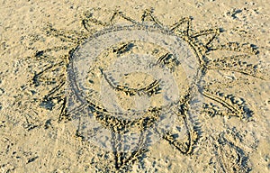 Child's drawing of smiling sun on yellow sand