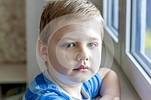 The child`s emotions. Children. Portrait of a boy. A sad expression on his face. Sad at the window.