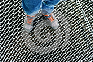 The child& x27;s feet are on the grates of the storm sewer. Top down view