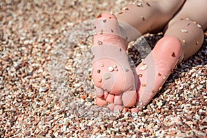 Child's feet on the pebbles beach