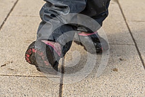 Child`s feet in rubber boots stained in spring mud