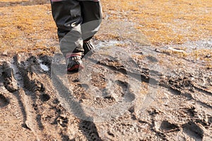 Child`s feet in rubber boots stained in spring mud