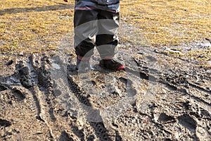 Child`s feet in rubber boots stained in spring mud