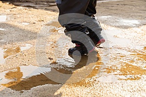 Child`s feet in rubber boots stained in spring mud