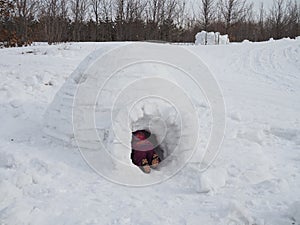 Child`s feet sticking out of the entrance to the snow house-igloo