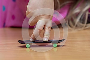 Child`s fingers on a fingerboard, wooden surface, close-up, selective focus. Fingerskate finger training. photo