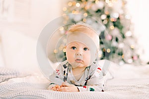 The child`s first Christmas. a pensive sad little boy is lying in a festive costume on the bed against the background of a