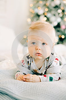 The child`s first Christmas. a pensive sad little boy is lying in a festive costume on the bed against the background of a