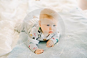 The child`s first Christmas. a pensive sad little boy is lying in a festive costume on the bed against the background of a