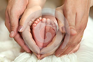 Child`s foot in mother and father`s hands. Pure love.