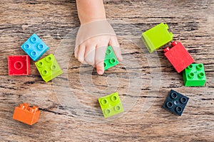 Child`s hand and colorful toy building cubes. Top view.