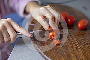 child\'s hand cuts a cherry tomato into slices