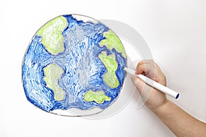 Child`s hand drawing planet Earth with a marker