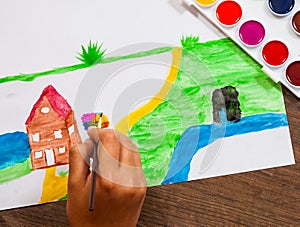 The child`s hand draws a picture with watercolors