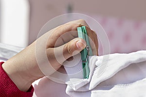 Child's hand that is hanging up clothes in the clothesline