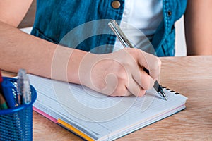 Child`s hand holding pen. The child writing letters in a noteboo