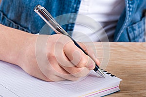 Child`s hand holding pen. The child writing letters in a noteboo