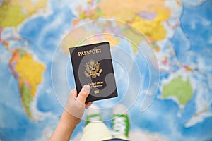 Child`s hand holding US passport. Map background. Ready for traveling. Open world