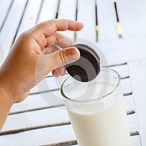 Child's hand with Oreo cookies extends to milk