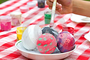 Child`s hand painting Easter eggs