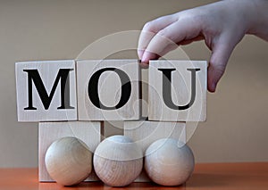 A child's hand places a large cube next to other cubes. MOU acronym concept photo