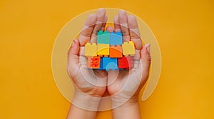 A child\'s hand playing with Lego. There are Legos scattered on the table with a orange background