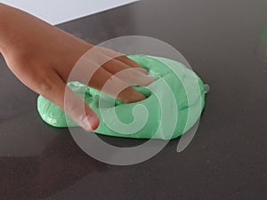 Child`s hand poking bright green slime