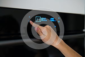 Child`s hand presses the buttons on the microwave. Closeup of black microwave control panel with cooking time