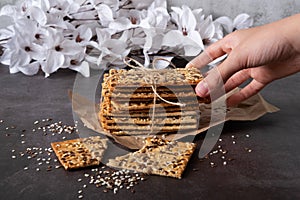 A child's hand reaches for grain bread with seeds of flax, sesame, sunflower