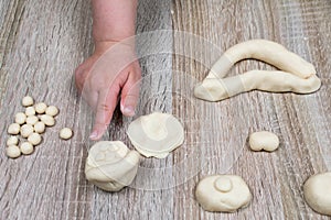 Child`s hand sculpts from salt dough, clay, plasticine on a wooden background. Children`s creativity. Manual creativity