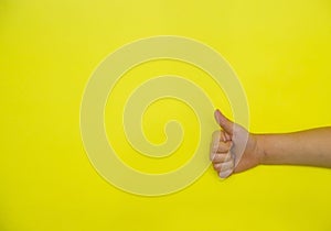 A child`s hand shows a raised thumb on a yellow background