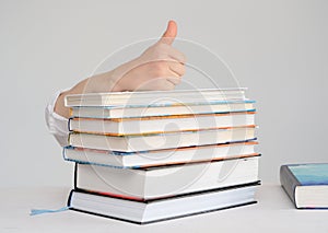 Child`s hand is on a stack of books shows a thumb up