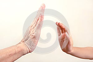 Child`s hand try to touch senior hand or old woman hand. select