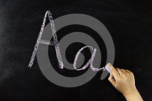 child's hand writes the letter A on the board