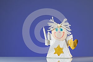 A child`s handicraft angel with a candle