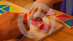 Child's hands compose wooden puzzle