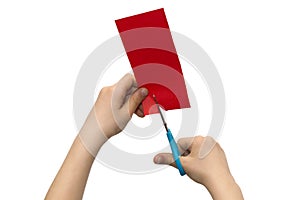 Child`s hands cutting colored red paper with scissors isolated o photo