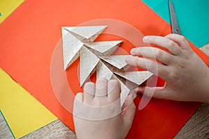 Child's hands cutting colored red paper with scissors isolated on white background