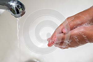 A child washing his hands with soap in bathroom sink