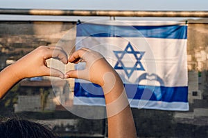 Child& x27;s Hands Form Heart on Israeli Flag with Sunlit Shadow.