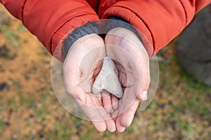 Child& x27;s hands hold a heart shaped stone close-up