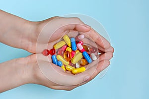 Child`s hands hold many colorful vitamins, capsules, supplements, pills