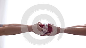 Child's hands hold out a small red gift box with a white bow in the woman's hands