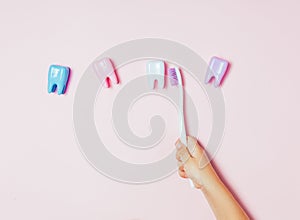 Child`s hands holding big tooth and toothbrush on pink backgroubd. Healty care teeth concept. Top view, flat lay. Copy