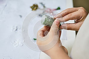 The child`s hands holding the jar with green sparkles for creating art work