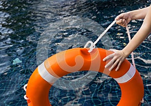 Child``s hands holding lifebuoy against dangerous dark water in swimming pool. Safety, parents fears concept